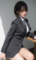 a woman in a suit and tie standing next to a table . 