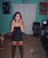 A woman in a black dress talking on a cell phone.