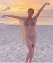 A Woman Waving on a Beach at Dusk