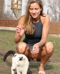 Blonde Beauty Kneeling Down to Pet a Cat