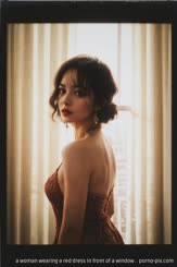 a woman wearing a red dress in front of a window . 